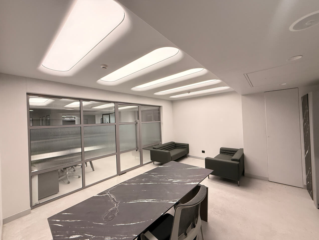 Contemporary workspace design in Vadodara featuring architectural lighting and stretch fabric ceiling systems for a bright, productive atmosphere.